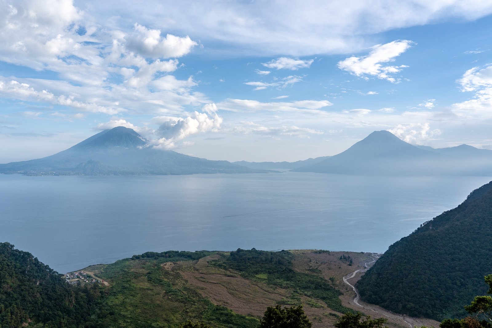 A wide angle shot of the mountains in front of the ocean under a clear blue sky 
 in Guatemala